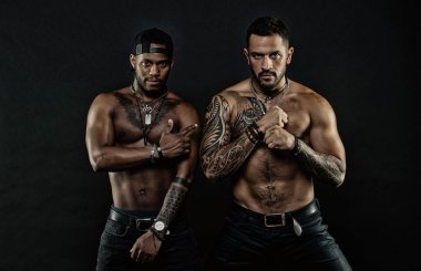 Atletler çıplak kas sandıkları ve pazı ile kendine güvenen yüzleri. Maço kas dövmeli torsolar ile çekici, koyu arka plan bak. Dövme sanat kavramı. Çocuklar sporcular seksi kas torsolar ile