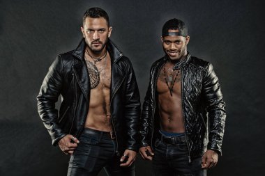 Maço kas torsolar ile deri ceketler, koyu arka plan çekici görünüyorsun. Adam kendinden emin kıl yüzlerle. Erkeklik ve vahşeti kavramı. Seksi kas torsolar erkeklerle vahşice bak