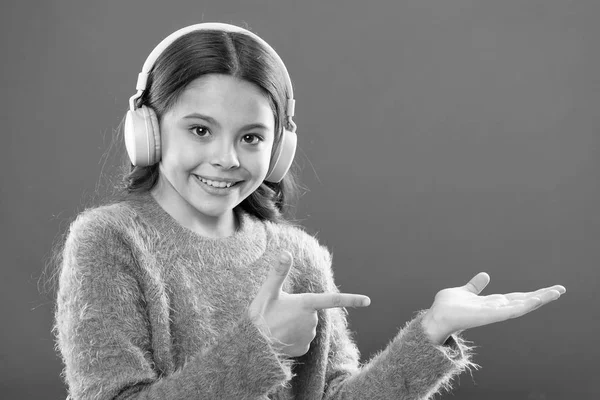 Fülhallgató vezeték nélküli modern technológia. Gyermek lány hallgatni zene vezeték nélküli fejhallgató mutatva a mutatóujját. Kap a zene előfizetésének. Élvezze a zene fogalma. Nézze meg a zene szolgáltatás másol hely — Stock Fotó