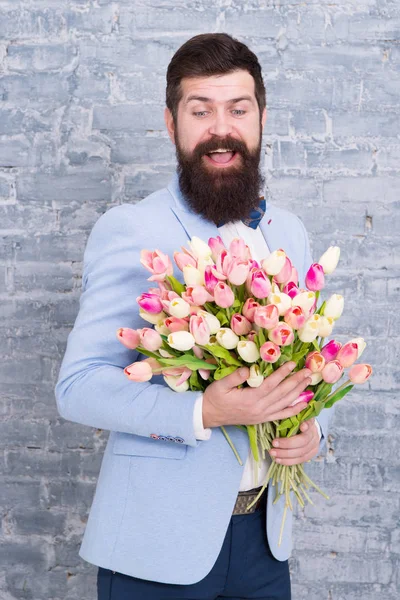 Macho getting ready romantic date. Tulips for sweetheart. Romantic gift. Man well groomed wear blue tuxedo bow tie hold flowers bouquet. Waiting for his girlfriend. Romantic man with flowers