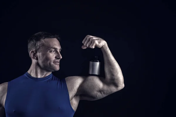 handsome bodybuilder man with muscular body holds pill jar, steroids