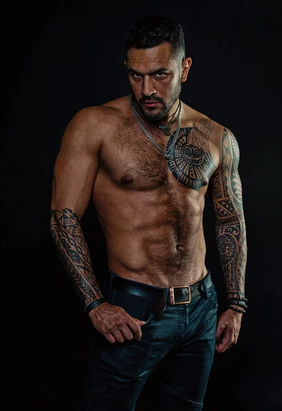 Sport or fitness and bodycare. Bearded man with fit tattooed body. Man with sexy bare torso in jeans. Tattoo model with six pack and ab. Athlete or sportsman with muscular chest and belly — Stock Photo, Image
