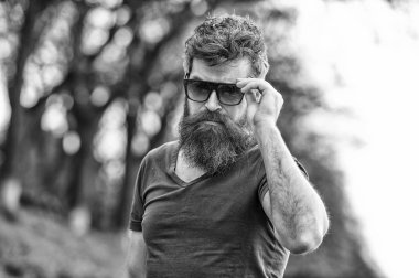 Sakallı hippi acımasız maço. Kuaför kavramı. Bıyık ciddi bir yüz emin doğa arka plan ile sakallı adam. Gözlüklü sakallı adam. Hipster karanlık moda güneş gözlüğü güvenen sakallı