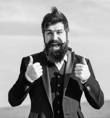 Başparmağını kaldır. Gelecekteki başarı. Erkek modası. Bıyıklı, vahşi, beyaz bir hippi. Sakallı, olgun bir hippi. İşadamı gökyüzüne karşı. Sakallı adam baş parmağını kaldırıyor. başparmak hareketi