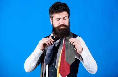 Doğru kravatı seçmeyi. Klasik bir tarz. Kravat, gömlek ve takım elbiseyle nasıl uyumlu olur? Sakallı bir hippinin mavi arka planda birkaç kravatı vardır. Kravat seçen sakallı adam. Beyefendinin rehberi.