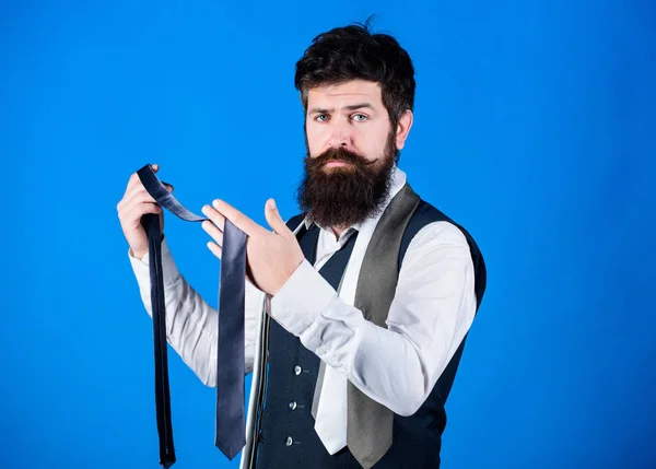 Bearded but elegant. Long bearded hipster choosing neckwear. Bearded man holding necktie. Cheerful man with unshaven bearded face and mustache hair with fashion accessories