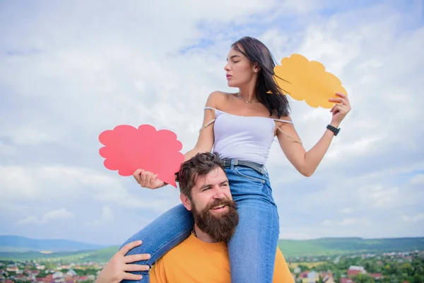 Un mot aux sages suffit. Couple aimant sourire avec des bulles comiques vides. Femme sexy tenir des bulles d'élocution tout hipster donnant son tour de dos de porc. Couple heureux amoureux sur ciel nuageux, espace de copie — Photo