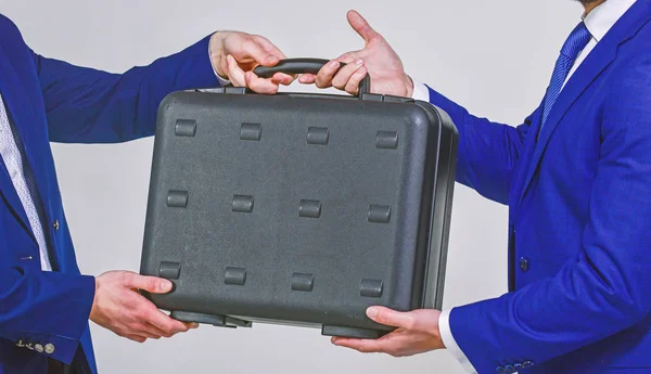 Business transfer concept. Male hand hold briefcase. Handover of case in hands of business partners. Handover of illegal goods. Illegal deal handover. Hands give briefcase for exchange or offer bribe