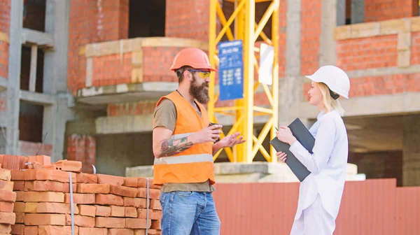 Relations entre les clients de la construction et les participants de l'industrie de la construction. Concept de communication de l'équipe de construction. Ingénieur femme et constructeur brutal communiquer fond du site de construction — Photo