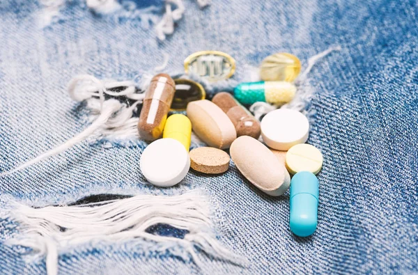 Dosis y adicción. Drogadicción. Concepto de medicina y tratamiento. Drogas sobre fondo denim. Conjunto de píldoras de colores. Mezclando medicamentos. Tratamiento rápido. Receta médica. Salud y enfermedad — Foto de Stock