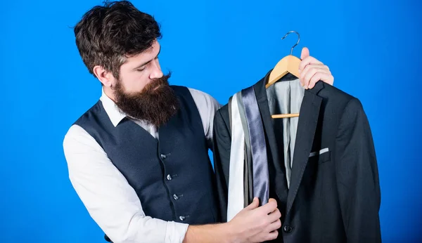 Shop assistant or personal stylist service. Matching necktie with outfit. Man bearded hipster hold neckties and formal suit. Guy choosing necktie. Perfect necktie. Shopping concept. Stylist advice