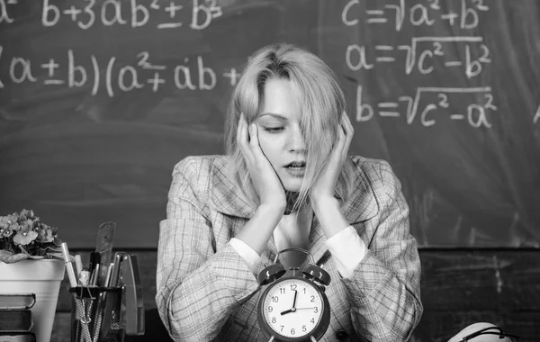 En la escuela. Enseñanza en casa. Mujer cansada. Estudio y educación. Escuela moderna. Día del conocimiento. mujer en el aula. De vuelta a la escuela. Día del maestro. profesor con despertador. El tiempo. comprobar el tim — Foto de Stock