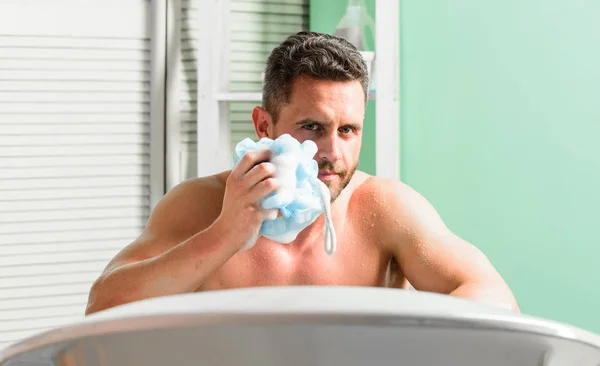 Лечение себя с горячей или теплой ванной может чувствовать себя высотой роскоши. Мужчина красивый мускулистый парень расслабляется в ванне. Побаловать и красота рутины. Концепция ухода за кожей. Принимать ванну с мылом — стоковое фото
