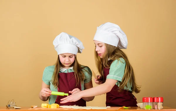 Chicas hermanas divirtiéndose con pasta de jengibre. Niños horneando galletas juntos. Delantales para niños y sombreros de chef cocinando. Las galletas caseras mejor. Receta familiar. Habilidad culinaria de cocina educación. Hornear galletas de jengibre — Foto de Stock