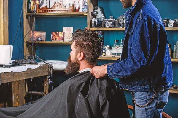 Człowiek z broda i wąsy siedzi w fryzjera, zużywalne na tle. Koncepcja fryzjera. Człowiek Brodaty klienta hipster fryzjera. Hipster z brodą oczekuje podczas Fryzjer osłona szyi z cape — Zdjęcie stockowe