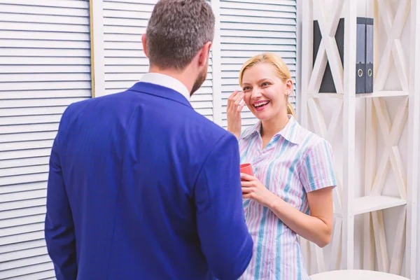 Dois de empresários atraentes, de pé ao lado um do outro, segurando uma xícara, sorrindo de pé no escritório. Casal de negócios sorridente no escritório conversando no coffee break. Reunião café . — Fotografia de Stock