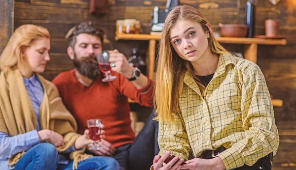 Chica rubia con grandes ojos en camisa amarilla vintage sentado en la sala de estar de campo casa de madera. Barbudo hombre y su esposa charlando, bebiendo y divirtiéndose mientras su hija se sienta sola —  Fotos de Stock