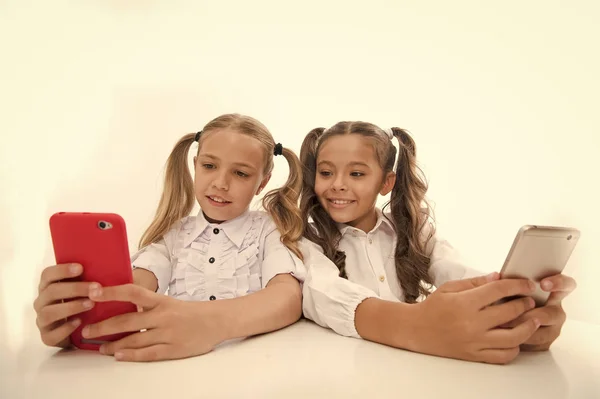 Blogueando en la escuela. niñas felices blogueando en teléfonos inteligentes. niñas pequeñas de vuelta a la escuela. tecnologías que facilitan la vida — Foto de Stock