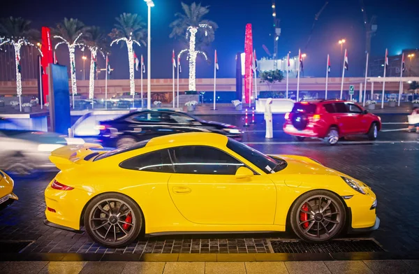Роскошный суперкар Porsche 911 Carrera 4 GTS желтого цвета припаркован рядом с торговым центром Дубая. Lamborghini является известным дорогим автомобилем марки — стоковое фото