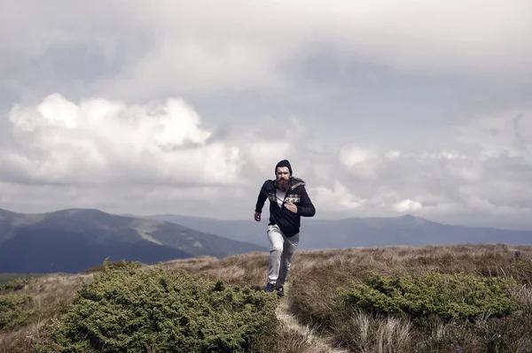 Людина біжить на зеленому лузі в горах на хмарному небі — стокове фото