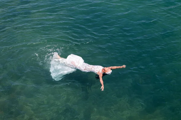 Bride white wedding dress lay sea water. Wet wedding dress hot sunny day. Bride happy enjoy summer vacation ocean background. Honeymoon at sea resort. Wedding abroad. Wedding ceremony seashore — Stock Photo, Image