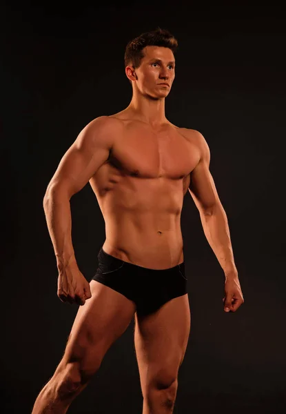 Athlete pose with fit body in briefs. Sportsman with sexy torso and chest. Man with six pack and ab muscles. Training and workout activity in gym. Sport or fitness and bodycare concept