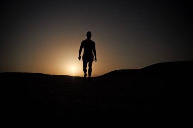 Adam yürüyüş günbatımı gökyüzü arka plan üzerinde.