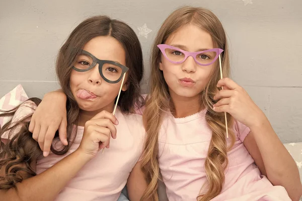 Humor brincalhão. Meninas crianças posando com grimaces adereços de cabine de fotos. Conceito de festa de pijama. Meninas amigas se divertindo pijama festa. Amigos bonito e alegre posando com óculos acessórios — Fotografia de Stock