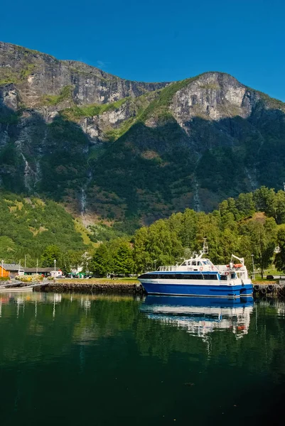 Piacere barca al molo sul paesaggio montano a Flam, Norvegia. Piccola nave in porto marittimo con montagne verdi. Viaggiare in acqua. Vacanze estive e vacanze. Vagabondaggio e scoperta — Foto Stock