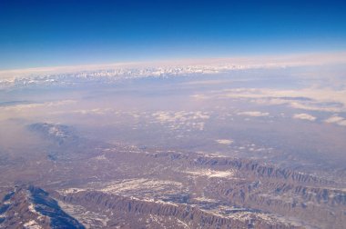 Dünya yüzeyinin üzerinde mavi gökyüzü, havadan görünümü. Çevre koruma ve ekoloji. Dağ manzarası. Yolculuk tutkusu ve seyahat. Yeryüzü cenneti