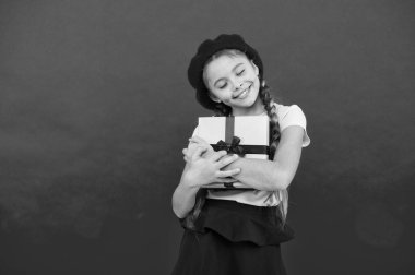 Küçük sevimli kız tatil hediyesi aldı. En iyi Noel hediyeleri. Çocuk hediyesini açmak için heyecanlı. Çocuk küçük kız kırmızı arka plan üzerinde kurdele ile hediye kutusu tutun. Kızı için Noel hediyesi