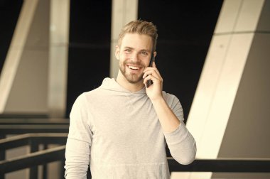 Ne harika bir haber. Sakal çağrı smartphone kentsel arka planı olan adam. Adam mutlu gülümseme kullanım akıllı telefon arkadaş iletişim kurmak için. Adam cep telefonu arama arkadaş kullanın. Hoş sohbet kavramı