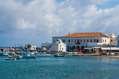 Mykonos, Yunanistan - 04 Mayıs 2010: Balıkçı tekneleri Denizi plajında. Bulutlu gökyüzü deniz köyünde. Kilise ve Yalı evleri. Adada tatil yaz. Yolculuk tutkusu ve kavram seyahat