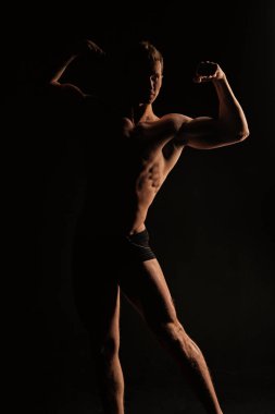 Vücut geliştirmeci karanlıkta kas vücut göster. Sporcu seksi gövde ve göğüs. Pazı ve triceps kaslı adam. Eğitim ve egzersiz etkinlik içinde jimnastik salonu. Spor ya da fitness ve welness kavramı