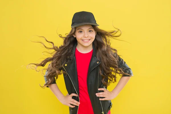 Girl adorable kid long wavy hair yellow background. Wind can also damage hair. Strong persistent winds can create tangles and snags in wavy and curly long hair. Protect your hair from wind damage — Stock Photo, Image