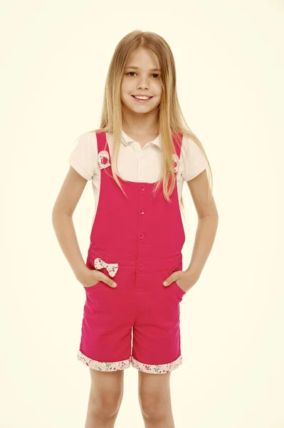 Estilo de moda e tendência. Menina pequena sorriso em macacão rosa isolado no branco. Criança sorrindo com longos cabelos loiros. Modelo de criança em geral na moda. Infância feliz e acolhimento de crianças — Fotografia de Stock