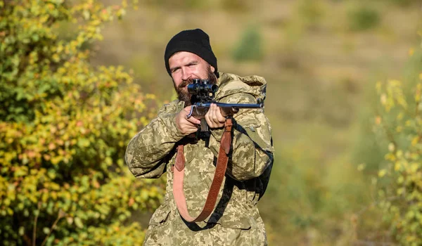 Bearded hunter spend leisure hunting. Focus and concentration of experienced hunter. Hunting masculine hobby concept. Man brutal gamekeeper nature background. Regulation of hunting. Hunter hold rifle