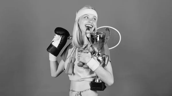 Wie man Zeit für alles findet. Sportartikelgeschäft. Sport für jeden Tag. Sportgeschäft Sortiment. Mädchen erfolgreiche moderne Frau halten goldenen Pokal des Sportmeisters und Ausrüstung blauen Hintergrund — Stockfoto