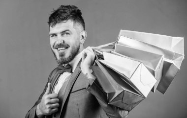 Seçkin butik. Adam sakallı zarif işadamı gri arka plan üzerinde alışveriş torbaları taşımak. Alışveriş daha neşeli hale getirin. Karlı fırsatlar siyah Cuma alışveriş keyfini çıkarın. İndirimli alışveriş keyfini satın alma