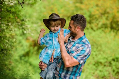 Ormanda mutlu bir baba. İnsan ve doğa. Aile günü. Dünya günün kutlu olsun. Eko çiftliği. Küçük çocuk çiftçilikte babasına yardım ediyor. Baba oğul çiftlikte kovboy şapkası takıyor. Lastik çizmeli çocuk. Çiftlik kovboyu