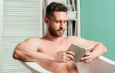 Tam bir rahatlama. Kişisel hijyen. Sinir sistemi banyo yarar. Rahatla konsepti. Adam kas gövde küvet dinlenmek ve kitap okuyun. Sıcak banyoda dinlenirken rahat adam kitap okuyor. Evde rahatlayın