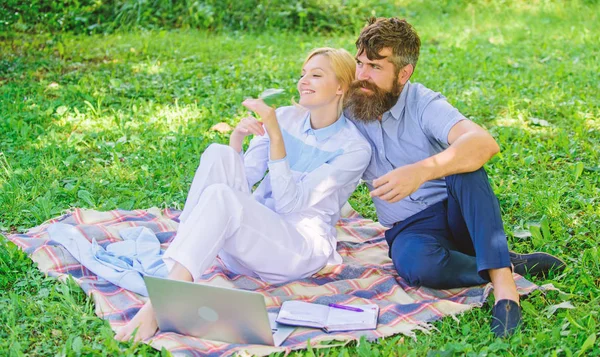 Family enjoy relax nature background. Couple bearded man and blonde woman relax nature while sit on green grass meadow. Couple with laptop relax natural environment. Relax and inspiration concept