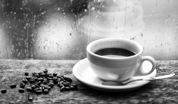 Podzimní zatažené počasí lepší nápoj na kofein. Káva se těší na deštivý den. Káva Ranní rituál. Čerstvá uvařená káva bílý hrnek a fazole na okenní parapet. Mokré skleněné okno a šálek horké kávy — Stock fotografie