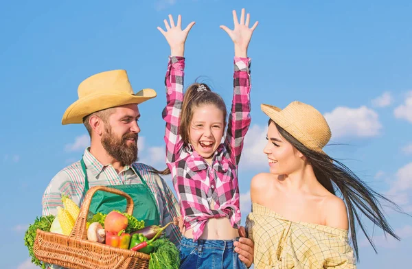 Family farm festival concept. Countryside family lifestyle. Farm market with fall harvest. Man bearded rustic farmer with kid and wife. Family father farmer mother gardener with daughter near harvest
