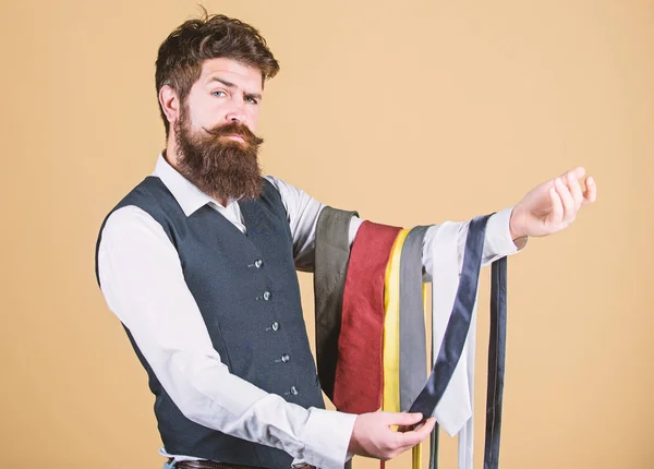 Um tipo com barba a escolher gravata. Uma gravata perfeita. Selecione o laço que tem cores de seu terno e camisa, bem como pelo menos uma outra cor para fornecer um sotaque. Homem barbudo hipster segurar algumas gravatas — Fotografia de Stock