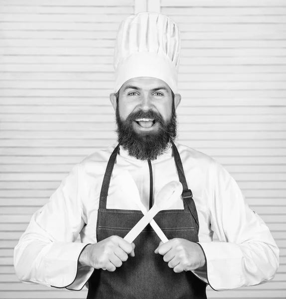 Geschirr und Kochkonzept. Lassen Sie uns Geschmack ausprobieren. Gewürze hinzufügen. Mann mit Bart in Kochmütze und Schürze hält Kochutensilien in der Hand. Kochen als Beruf. Hipster bärtiger Koch hält Kochlöffel in der Hand — Stockfoto