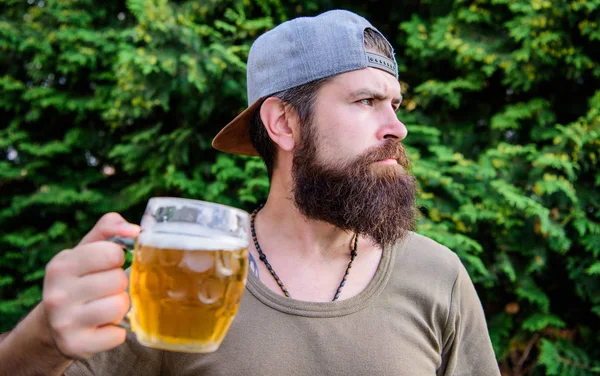 A beber cultura. Hipster segurando caneca de cerveja. Um hipster barbudo a beber cerveja na natureza de verão. Bebedor de Hipster. Homem Hipster com cerveja artesanal. Homem bruto com hábitos de beber. Beber apenas cerveja pesada — Fotografia de Stock