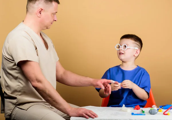Medicine concept. Kid little doctor sit table medical tools. Health care. Medical examination. Boy cute child and his father doctor. Hospital worker. First aid. Medical help. Trauma and injurie — Stock Photo, Image