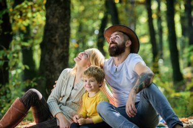 Birlikte doğayı keşfedelim. Aile günü konsepti. Anne baba ve çocuk ormanda yürürken dinleniyorlar. Aile pikniği. Anne baba ve küçük oğlu ormanda piknik yaparlar. Doğada bahar pikniği için güzel bir gün.