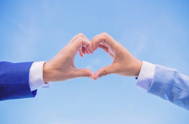 El kalp hareketi parmaklarını kullanarak şekil oluşturur. Kalp şekli hareketi simgesinin aşk ve romantizm erkek elinde. Aşk sembolü kavramı. Kalp şekli mavi gökyüzü arka planda bir alkış